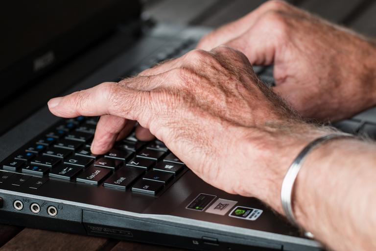 Laptop, ruky na klávesnici